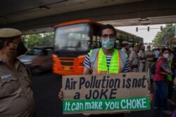FILE - A student activist holds a placard as he participates in a protest march against climate change in New Delhi, India, March 19, 2021.