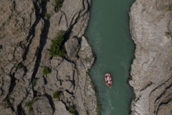 FILE - People raft on the Vjosa River near Permet, Albania, June 25, 2019. Some tout hydropower as a reliable, cheap and renewable energy source, but critics say the benefits of hydropower are overstated and are outweighed by the harm dams can do.