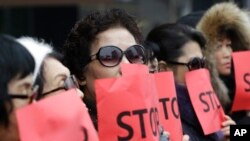 FILE - In this Jan. 26, 2015, photo, defectors from North Korea cover their faces with placards as a safety precaution for their relatives still living in the North, during a rally to protest human rights abuses in North Korea, in Seoul, South Korea.