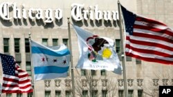 FILE - Flags wave near the Chicago Tribune Tower in Chicago, April 12, 2006. Newspaper publisher Tribune, which owns the Chicago Tribune, the Baltimore Sun and other newspapers, said Feb. 16, 2021, it has agreed to be sold to Alden Global Capital.