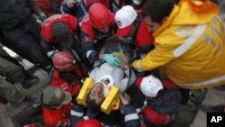 Emergency service workers carry an earthquake survivor during rescue operations in Ercis, near the eastern Turkish city of Van, October 24, 2011.
