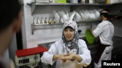 Seorang pekerja tuna rungu di Restoran Atfaluna, Gaza, menggunakan bahasa isyarat untuk berkomunikasi. (Reuters/Suhaib Salem)