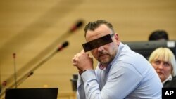 Lutz Bachmann, center, co-founder of Germany's PEGIDA movement, is flanked by his lawyer Katja Reichel as he waits for the opening of his trial in the courtroom of the local court during the beginning of the trial on accusations of incitement in Dresden, eastern Germany, Tuesday, April 19, 2016.