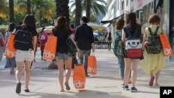 FILE - Tourists carry shopping bags as they walk along Lincoln Road Mall, a pedestrian area featuring retail shops and restaurants in the South Beach section of Miami Beach, Florida, Feb. 3, 2016.