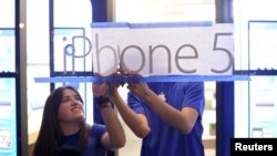Apple employees hang an iPhone 5 sign at one of the company's retail locations shortly before sales began in San Francisco, California, September 21, 2012. Apple fans queued around city blocks worldwide on Friday to get their hands on the new iPhone 5 - but grumbles about inaccurate maps tempered the excitement.