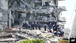 Para petugas penyelamat masih terus melakukan pencarian korban di antara puing-puing gedung apartemen "Champlain Towers South condominium" di Miami, Florida yang roboh hari Kamis (24/6). 