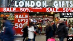 FILE - Shoppers pass a sale sign on Oxford Street in London, Dec. 22, 2014. 