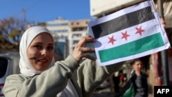 在叙利亚海滨城市拉塔基亚，一位女子亮出叙利亚反对派的旗帜。(2024年12月10日)