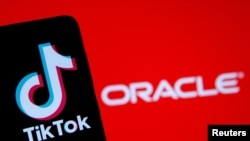 A smartphone with the Tik Tok logo is seen in front of a displayed Oracle logo in this illustration taken, Sept. 14, 2020. 