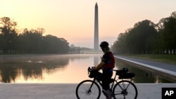 Велосипедист гледа како изгрева сонцето на Националното шеталиште во Вашингтон, 25 април 2020 година (Фото: АП)