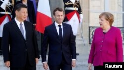 French President Emmanuel Macron, German Chancellor Angela Merkel and Chinese President Xi Jinping leave following a meeting at the Elysee Palace in Paris, France, March 26, 2019. 