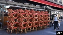 A man wearing a protective face mask walks in front of a closed restaurant in Paris on May 30, 2020, as France eases lockdown measures taken to curb the spread of the COVID-19