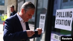Britain's Labour Party leader Keir Starmer puts on a protective mask as he arrives at a polling station to vote during local elections, in London, May 6, 2021. 