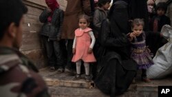 Women and children exit the back of a truck to be screened by U.S.-backed Syrian Democratic Forces (SDF) after being evacuated out of the last territory held by Islamic State militants, in the desert outside Baghouz, Syria, Feb. 27, 2019. 