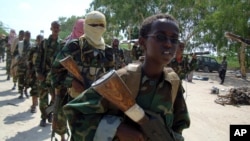 FILE - A youth leads a group of hard-line Islamist Al Shabab fighters as they conduct military exercises in northern Mogadishu's Suqaholaha neighborhood, Somalia, Jan. 1, 2010. 