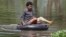 A Cambodian woman rides on a tire tube in a flooded road in Kampong Thom province, about 120 kilometers (75 miles) north of Phnom Penh.