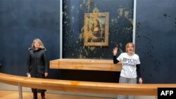 Dua aktivis lingkungan dari kolektif "Riposte Alimentaire" melakukan aksi protes dengan melepar sup ke Lukisan Mona Lisa di museum Louvre di Paris, pada 28 Januari 2024. (Foto: David Cantiniaux/AFPTV/AFP)