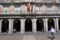 A man wearing a protective face mask walks at the usually crowded Plaza Mayor in central Madrid, Spain, March 14, 2020, after authorities ordered all shops in the region be shuttered die to the coronavirus.