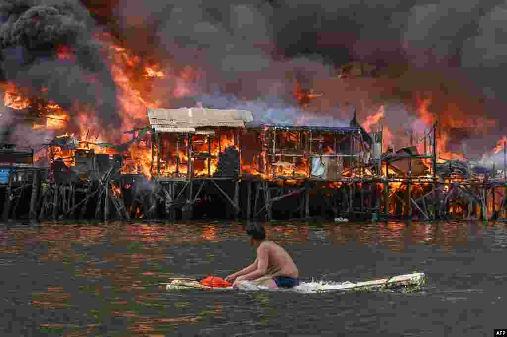 A man watches houses on fire at Tondo in Manila, Philippines.&nbsp;Raging orange flames and thick black smoke billowed into the sky, as fire ripped through hundreds of houses in a closely built slum area of the capital.