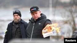 Pemimpin Partai ekstrem kanan asal Denmark, Rasmus Paludan, membakar Al-Qur'an di luar Kedutaan Besar Turki di Stockholm, Swedia, Sabtu, 21 Januari 2023. (Foto: Fredrik Sandberg/TT News Agency/via REUTERS)