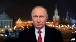 In this photo released by Kremlin Press service via Sputnik agency, Russian President Vladimir Putin speaks during a recording of his annual televised New Year's message in the Kremlin in Moscow, Jan. 31, 2018.