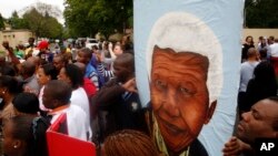 Sekelompok warga yang berduka cita membawa gambar pemimpin Afrika Selatan Nelson Mandela, menari dan menyanyi di luar rumahnya di Johannesburg (6/12). (AP/Themba Hadebe)
