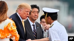 Presiden AS Donald Trump (dua dari kiri) berjabat tanagn dengan Hideki Mizuta (kanan), kapten kapal Jepang "J.S. Kaga" saat hendak bertolak meninggalkan kapal tersebut di Yokosuka, selatan Tokyo, 28 Mei 2019.