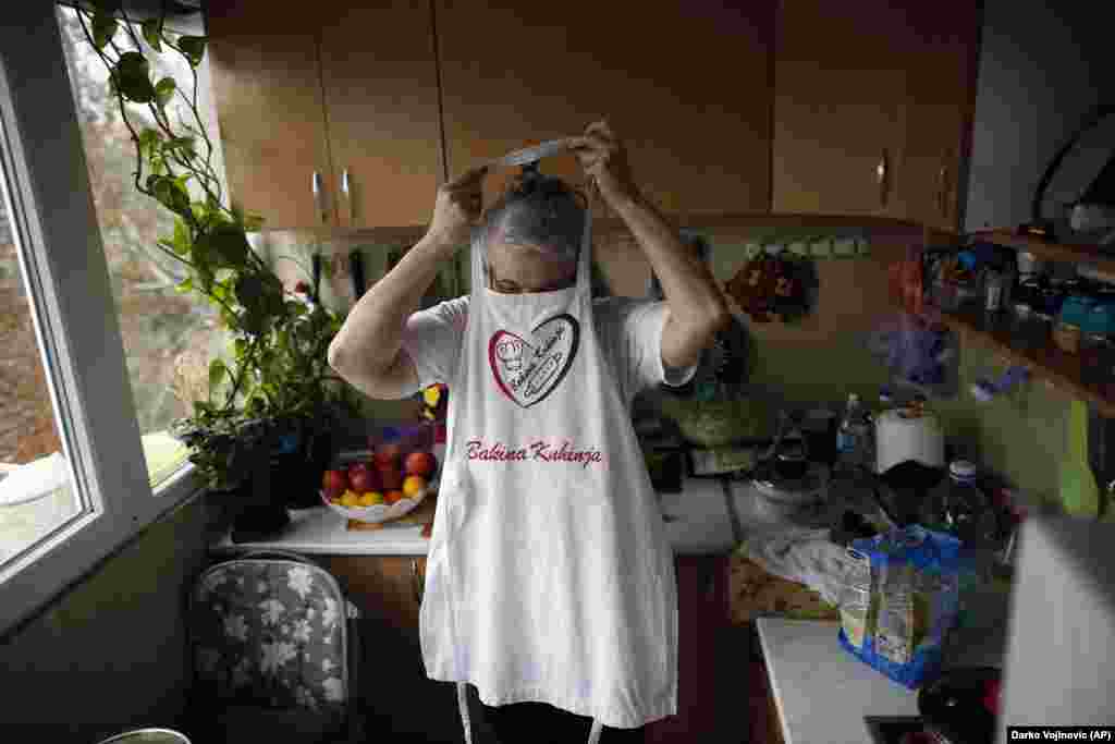 Jelena Petrovic puts on an apron as her husband returns with groceries.