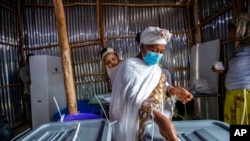 FILE - A mother carries her baby on her back as she casts her vote in the general election at a polling center near Entoto Park on the outskirts of Addis Ababa, Ethiopia, June 21, 2021.