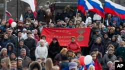 People gather with Russian and Crimean flags awaiting a concert where Russian President Vladimir Putin later made an appearance in Sevastopol, Crimea, March 14, 2018. (AP Photo/Alexander Zemlianichenko)