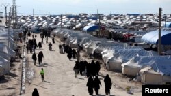 FILE - Women walk through al-Hol displacement camp in Hasaka governorate, Syria, April 1, 2019. 