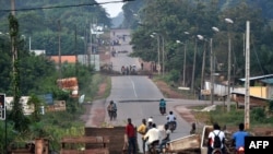 People stand near barricades as they protest against a third term of incumbent Ivory Coast President at the entrance of Daoukro, Nov. 2, 2020.