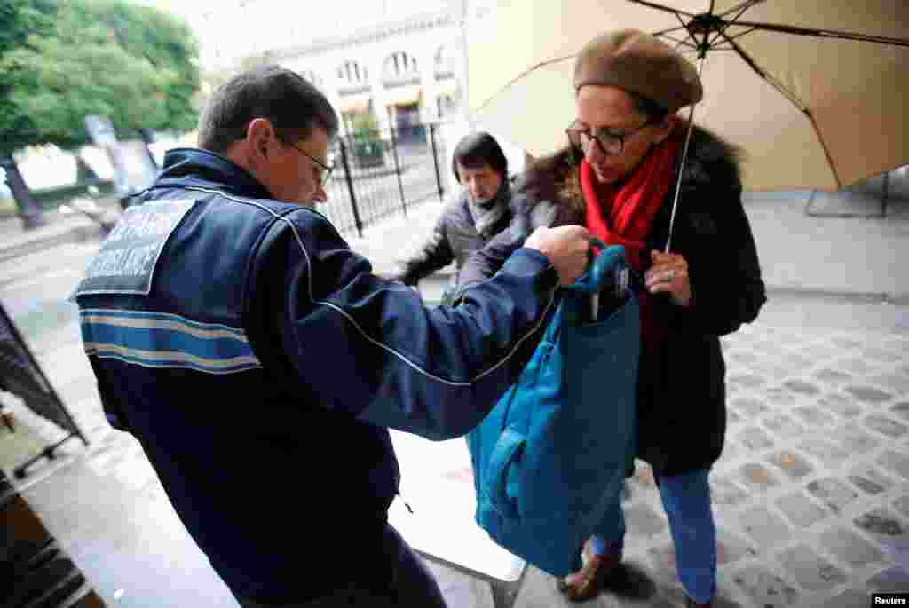 A municipal employee checks bags at the entrance of a polling station in Paris, May 7, 2017.