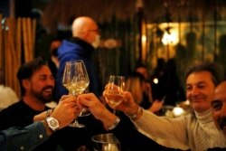 Customers toast as they dine in a restaurant in Milan, Italy, Jan. 15, 2021. The restaurant is one of several that decided to stay open despite anti-COVID evening closure restrictions that allow only takeout orders.