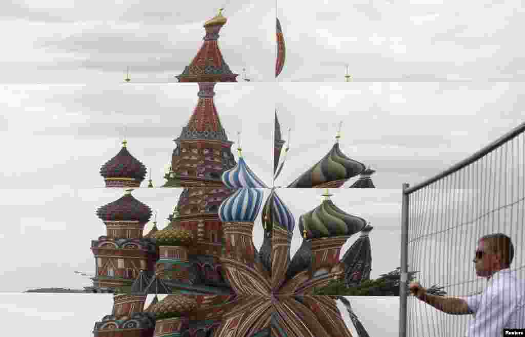 Refleksi dari gereja Katedral St Basil tampak pada cermin pavilliun, sementara seorang penjaga keamanan Rusia membuka pintu gerbang dekat cermin paviliun yang dibangun di Lapangan Merah di kota Moskow.