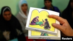 FILE - A counselor holds up cards used to educate women about female genital mutilation (FGM).