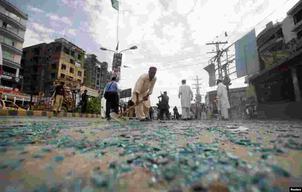 Rescue workers collect shattered glass from the site of the bomb blast on University Road in Peshawar, April 29, 2013.
