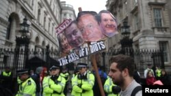 Demonstrators hold placards during a protest outside Downing Street in Whitehall, central London, Britain, April 9, 2016. 