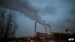 FILE - Cars pass the Shanghai Waigaoqiao Power Generator Company coal power plant in Shanghai, March 22, 2016.