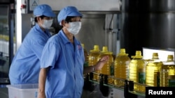 2018年7月4日，中国山东省曲阜市粮油工业和进出口公司工厂的工人在瓶装豆油的生产线上。这些豆油是用美国大豆提炼的。