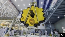 In this April 13, 2017 photo provided by NASA, technicians lift the mirror of the James Webb Space Telescope using a crane at the Goddard Space Flight Center in Greenbelt, Md. (Laura Betz/NASA via AP)