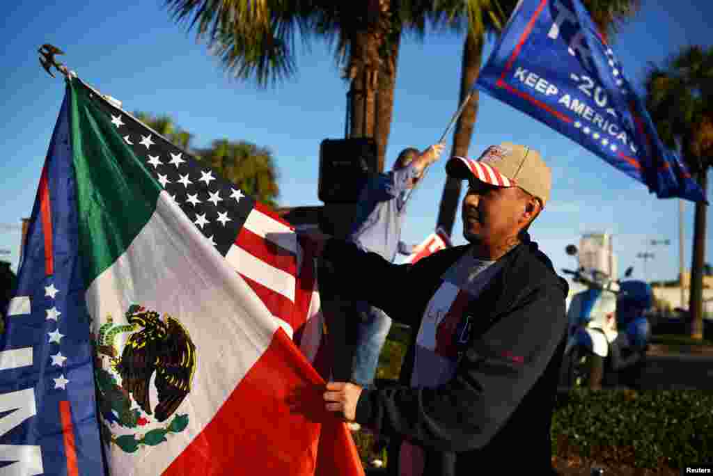 Jose Casares, 32, waves flags in support of Trump as voters line up at a polling station during Election Day in Houston, Texas, Nov. 3, 2020. 