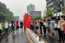 Anti-coup protesters hold a Chinese flag before burning it down during a demonstration against China in Yangon, Myanmar, April 5, 2021.