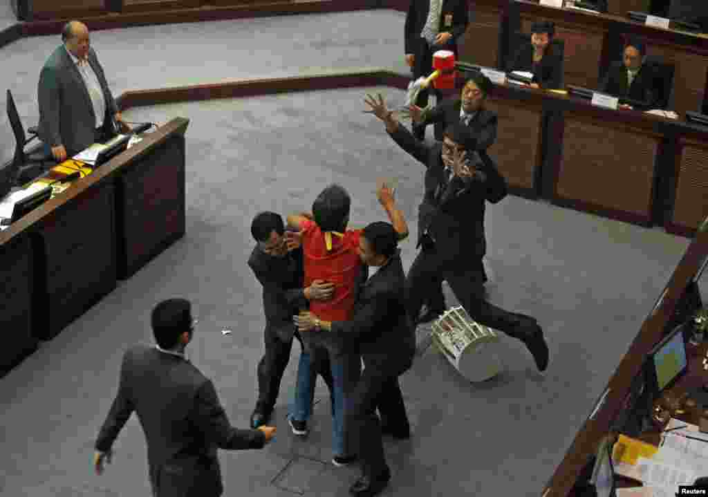 Pro-democracy lawmaker Leung Kwok-hung is stopped by security guards as he throws a plastic hammer towards Hong Kong Chief Secretary Carrie Lam during a meeting on proposing electoral reforms at the Legislative Council in Hong Kong.