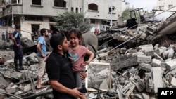 7일 하마스의 공습을 받은 가자지구 건물 앞에서 한 남성이 울고 있는 아이를 안아 주고 있다. 