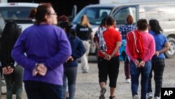 Government agents lead suspects in custody toward a restroom during an immigration sting at Corso's Flower and Garden Center in Castalia, Ohio, June 5, 2018.