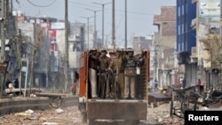 Policemen move in a truck in a riot affected area after clashes erupted between people demonstrating for and against a new citizenship law in New Delhi, India, Feb. 26, 2020. 