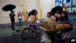 A man on a bike stops to buy plantains from a vendor in San Salvador, El Salvador, Aug. 20, 2018.