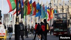 FILE - People ride a bus past flags representing Commonwealth countries next to Westminster Abbey in London on March 13, 2023. The Commonwealth is scheduled to meet Oct. 21-25, 2024, in Samoa.