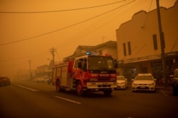 FILE - A fire truck moves up the main street of the New South Wales town of Bombala which is shrouded in smoke from nearby bushfires on Dec. 31, 2019.